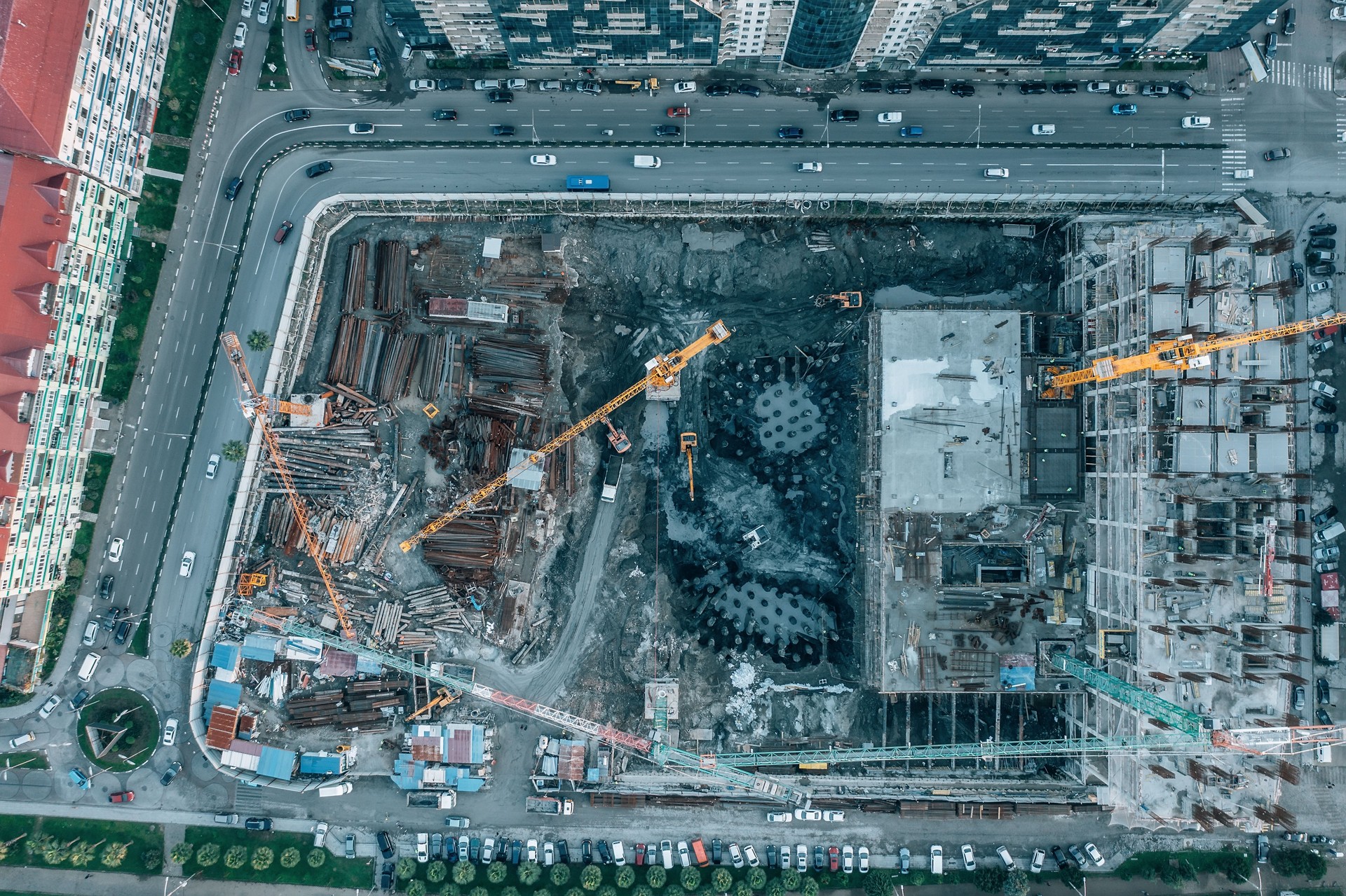 Construction site aerial top view from drone. Tower cranes and industrial machinery, housing development